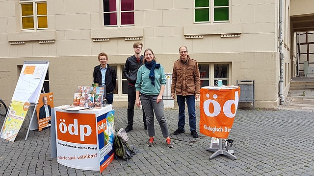 Gruppenfoto mit vier Menschen vor einem Infostand am Burgplatz