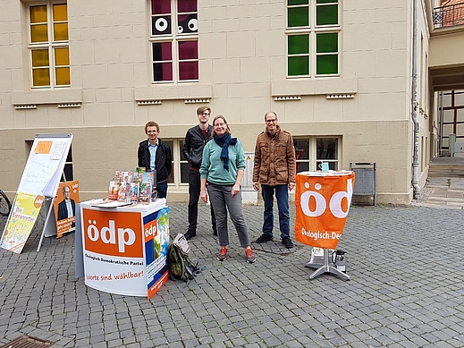 Gruppenfoto mit vier Menschen vor einem Infostand am Burgplatz